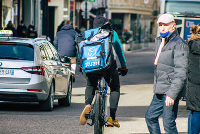 Rear view of people riding bicycle on city street