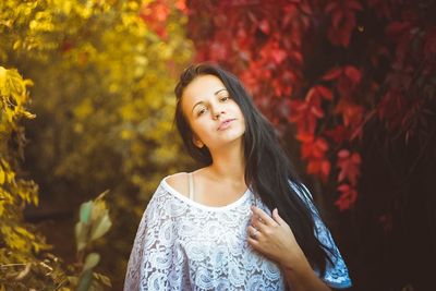 Beautiful young woman standing against trees during autumn