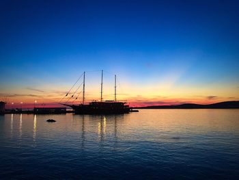 Silhouette sailboats in sea against sky during sunset