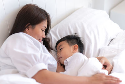 High angle view of mother and son lying on bed at home