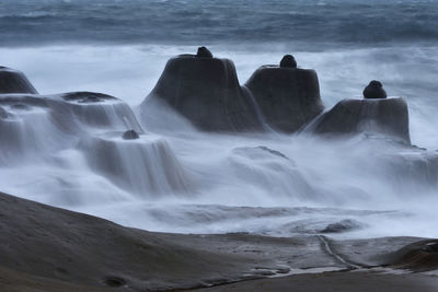 Scenic view of waterfall by sea