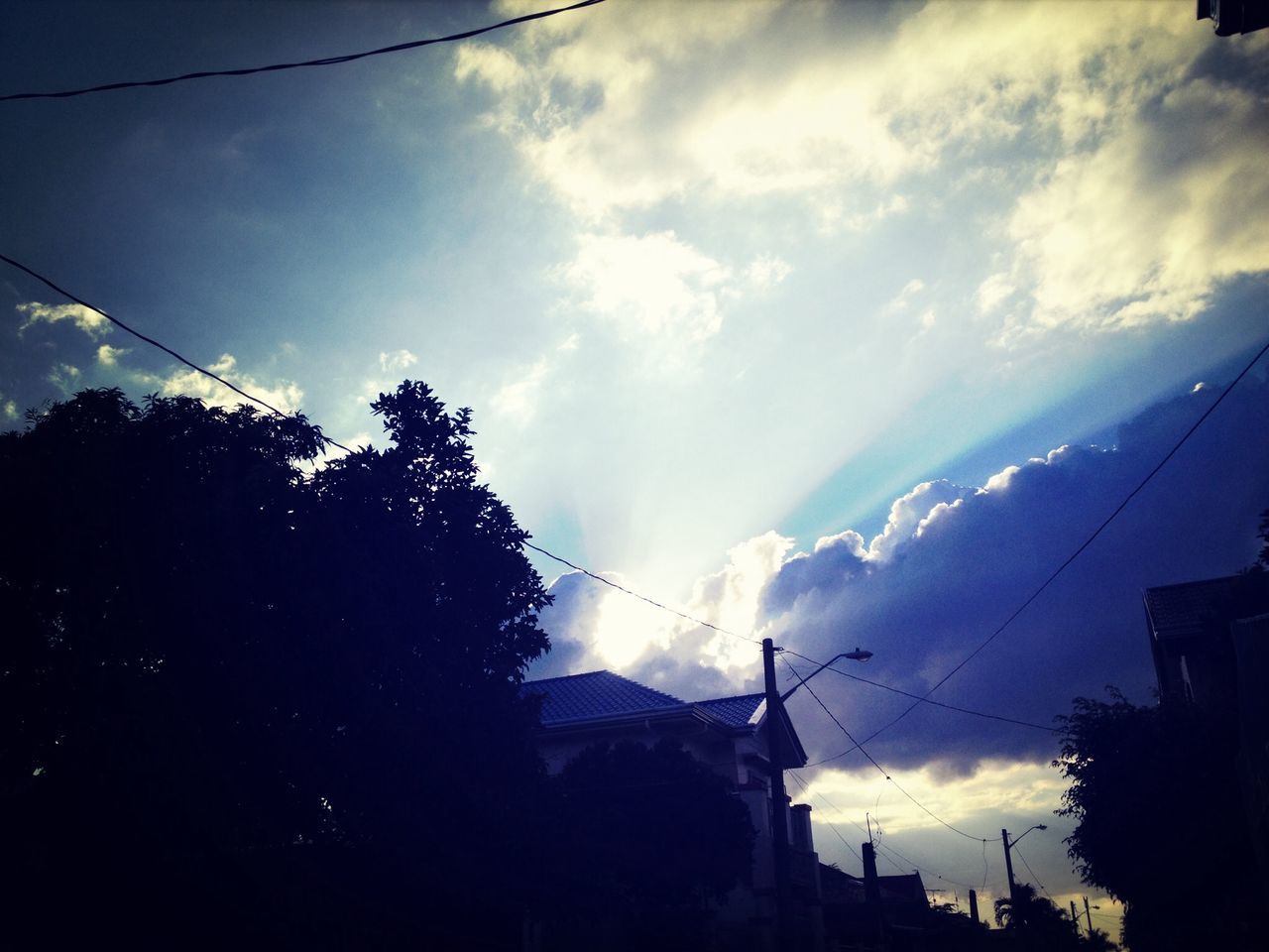 sky, power line, cloud - sky, silhouette, low angle view, tree, building exterior, cable, electricity, electricity pylon, cloudy, built structure, architecture, cloud, power supply, nature, beauty in nature, house, dusk, weather