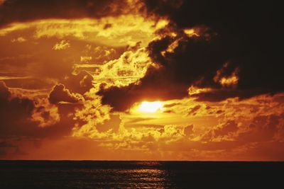 Scenic view of sea against dramatic sky during sunset