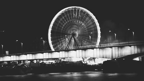 Illuminated ferris wheel against sky at night