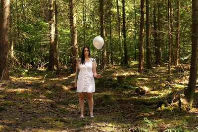 Woman standing by tree in forest