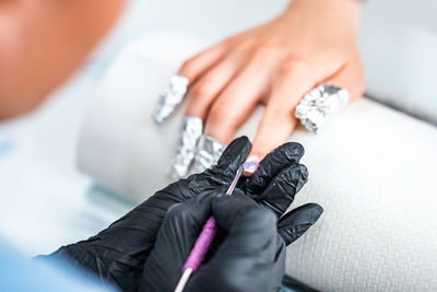 Close-up of woman doing nail art of customer at table