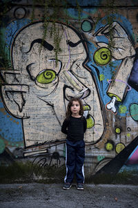 Full length portrait of woman standing against graffiti wall