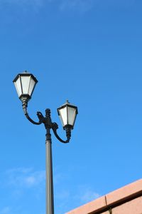 Low angle view of street light against blue sky.