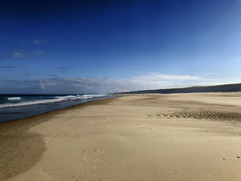 Scenic view of beach against blue sky