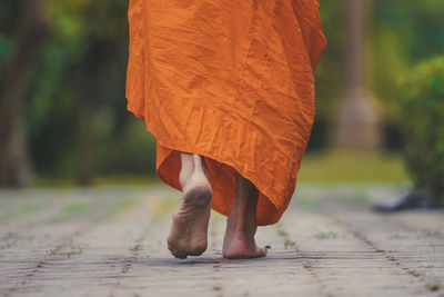 Low section of monk walking on footpath