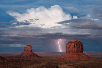 A vivid lightning bolt strikes from a monsoon storm over monument valley, arizona