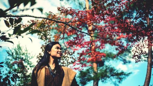 Low angle view of woman looking away against trees