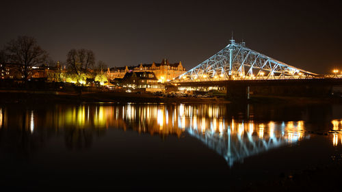 Illuminated bridge over river against sky at night