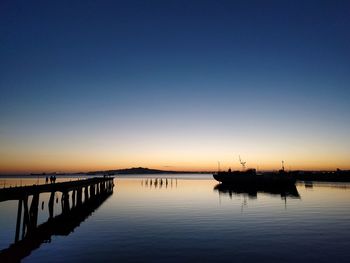 Silhouette sailboats in lake against clear sky during sunset