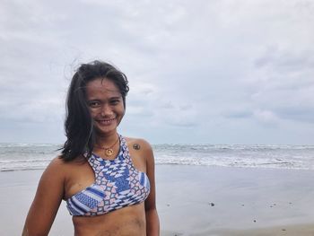 Portrait of smiling young woman standing at beach