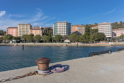 View of cityscape by river against blue sky