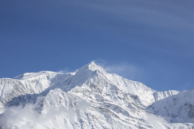 Scenic view of snowcapped mountains against blue sky