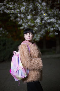 Woman wearing fur coat while looking away outdoors