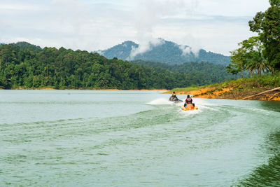 People riding in boat against sky