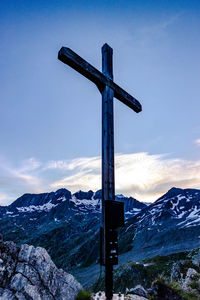 Cross on snowcapped mountain against sky