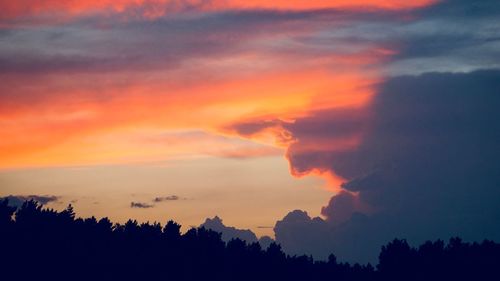 Low angle view of silhouette trees against dramatic sky