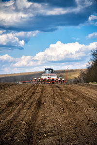 Car on dirt road by land against sky