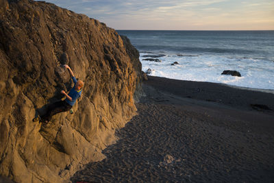 High angle view of man climbing rock at beach