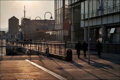 People walking on road against buildings in city