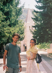 Portrait of young couple standing against trees