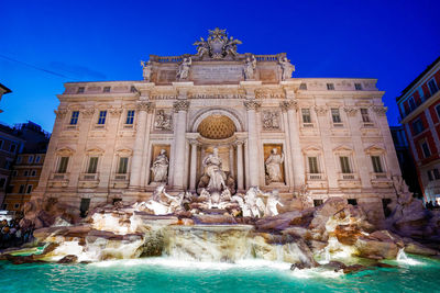Low angle view of trevi fountain in city at dusk