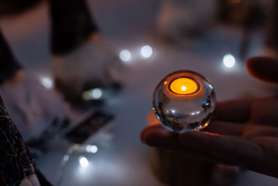 Close-up of hand holding illuminated candles