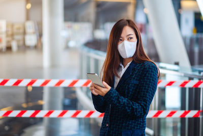 Young woman using mobile phone while standing on laptop