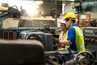 Engineers or technicians are watching the operation of the machinery through the industrial tablets.