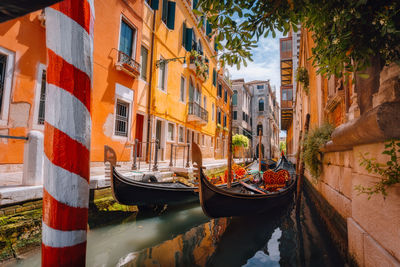 Boats moored in canal amidst buildings in city