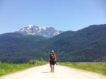 Rear view of man on road against mountain range