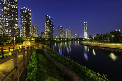 River amidst illuminated buildings against sky at night