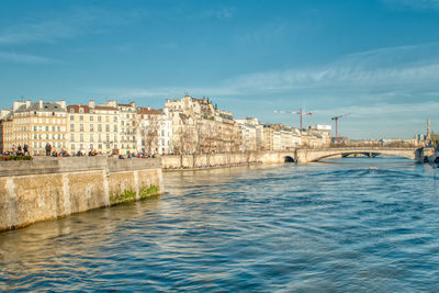 View of buildings by sea against blue sky