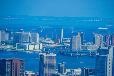 High angle view of modern buildings in city against blue sky