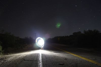 Light trails on road against sky at night