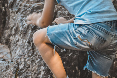Midsection of boy climbing a rock 