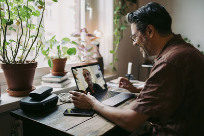 Side view of man using laptop on table