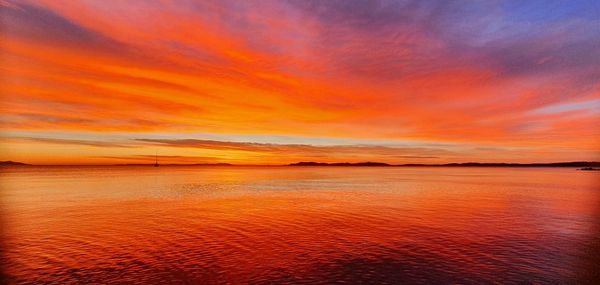 Scenic view of sea against dramatic sky during sunset