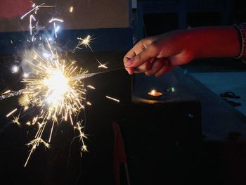 Hand holding illuminated fire crackers at night