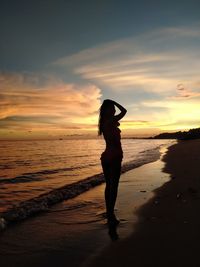 Silhouette man standing on beach against sky during sunset