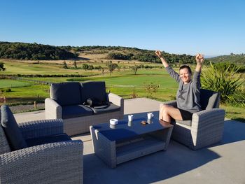 Full length of man sitting on seat against sky