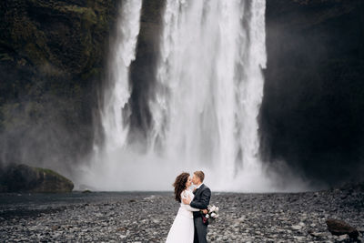 Woman standing against waterfall