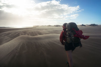 Rear view of man walking on mountain against sky