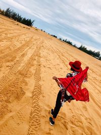 High angle view of woman looking away holding scarf standing at desert