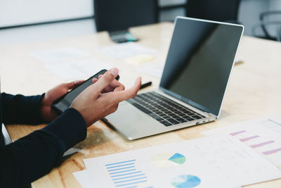 Midsection of woman using laptop on table