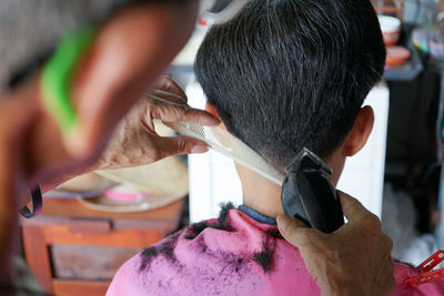 Closeup rear view head of man having a hair cut with battalion and comb